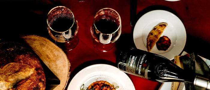 Two glasses of red wine, bread, and plated food at Leku Ona Restaurant Boise Idaho.