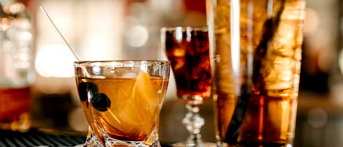 Close-up of cocktails at Leku Ona Restaurant Boise Idaho, with orange peel and cherries garnish.