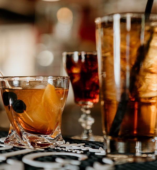 Three cocktails at Leku Ona Restaurant Boise Idaho, featuring an Old Fashioned with orange garnish.