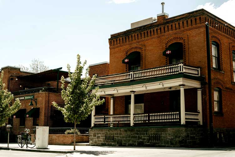 Red brick building with large porch, green trim, trees—Leku Ona Restaurant Boise Idaho.