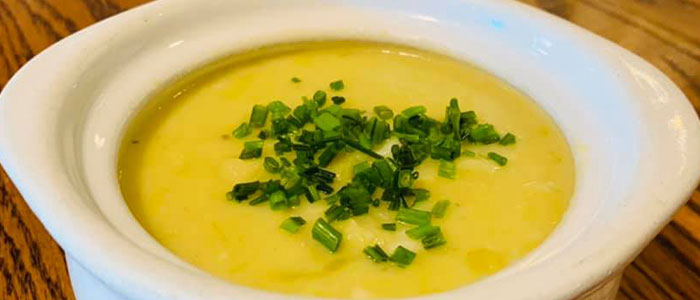 A bowl of creamy yellow soup at Leku Ona Restaurant Boise Idaho, topped with green chives.
