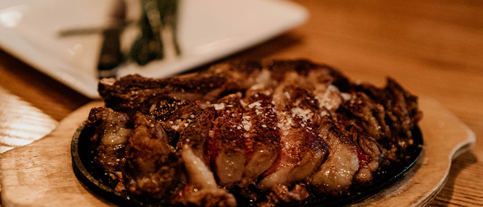 Sliced grilled steak at Leku Ona Restaurant Boise Idaho, served on a wooden platter.