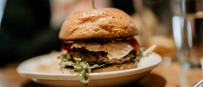 Close-up of a burger at Leku Ona Restaurant Boise Idaho, topped with lettuce, cheese, and tomato.