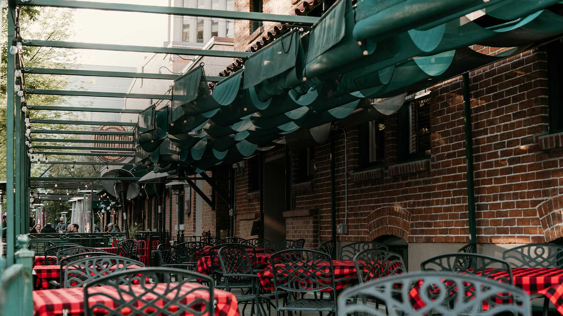 Outdoor patio at Leku Ona Restaurant Boise Idaho with red plaid tablecloths and a brick wall.