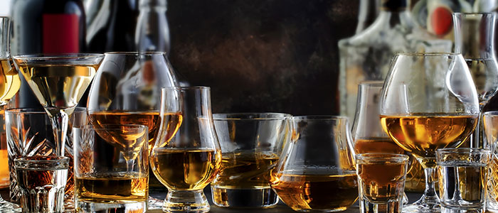 Various glasses of whiskey and spirits at Leku Ona Restaurant Boise Idaho on a reflective surface.